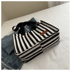 Close-up of black and white striped canvas tote with brown leather fashion tag detail