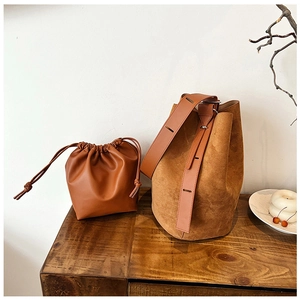 Close-up of retro brown bucket bag and pouch set with matte texture and wide strap