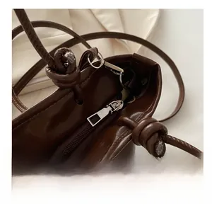 Close-up of smooth metal zipper and knotted shoulder strap on dark brown vintage bag