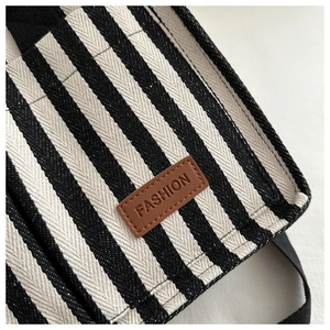 Detail of striped canvas tote with vertical lines and brown leather fashion patch