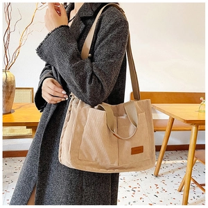 Detail of beige corduroy tote bag with fashion leather patch and adjustable strap