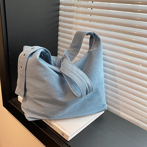 Grand sac cabas en jean bleu clair avec œillets métalliques sous une lumière naturelle