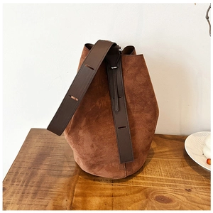 Close-up of vintage brown suede bucket bag with leather strap and drawstring detail
