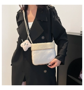 Close-up of white plush crossbody bag with star-shaped smiley charm and fuzzy texture