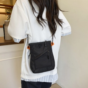 Detail of black nylon crossbody bag featuring vibrant orange accents and water-resistant fabric