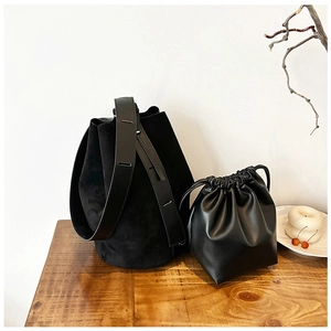 Macro view of minimalist black bucket bag with matte texture on a wooden table surface