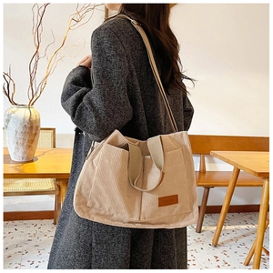 Detail view of cream corduroy tote bag featuring front dual pockets and a fashion leather patch