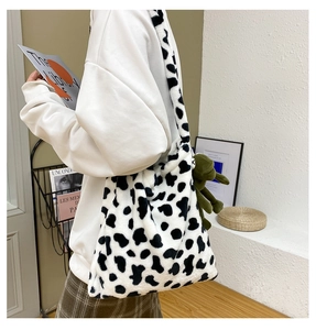 Detail of plush faux fur tote bag with cow print and green frog plush toy charm