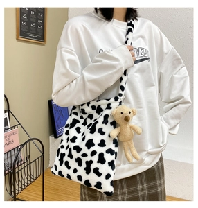Detailed view of fluffy cow print tote bag with a cute brown plush bear charm