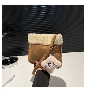Detail of vintage brown faux suede shoulder bag with plush shearling trim and cute charm
