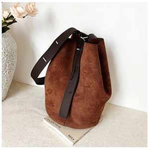 Detailed shot of brown frosted suede bucket bag texture and wide leather shoulder strap