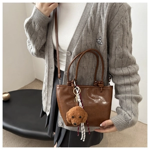 Brown vintage faux leather tote with plush dog charm and stylish striped scarf detail