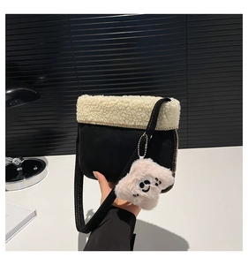 Detail of plush black suede crossbody bag with sherpa trim and cute monster charm