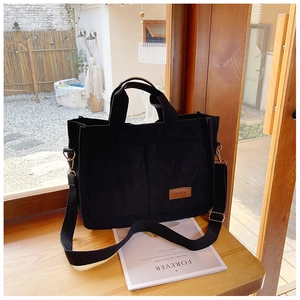 Detail of black corduroy tote bag showing front pockets and leather fashion label