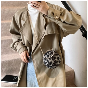 Sac boule chic en fausse fourrure léopard porté par un mannequin en trench et jean