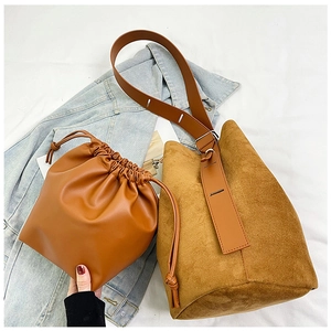 Macro shot of large brown matte bucket bag and drawstring pouch set on denim backdrop