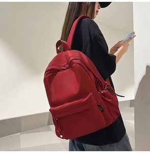 Side view of red large capacity nylon backpack on model showing durable shoulder straps
