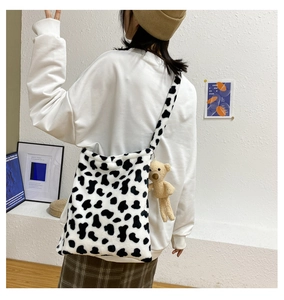 Detailed back view of plush cow print crossbody bag with cute teddy bear charm