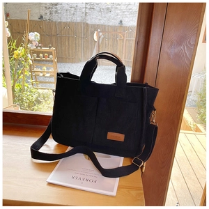 Close-up of black corduroy tote bag with adjustable strap and fashion leather patch