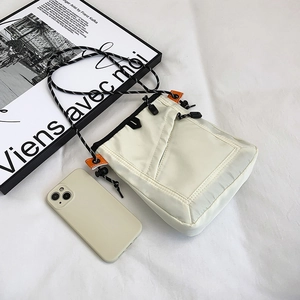 Detail view of beige nylon mini crossbody bag with rope strap and orange accent