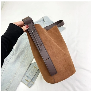 Detail of caramel brown suede bucket bag featuring adjustable leather shoulder strap