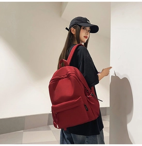 Detail view of a large red canvas backpack with padded straps and functional zip pockets