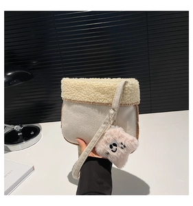 Detail of off-white plush crossbody bag with sherpa trim and pink smile face pendant