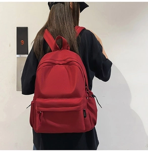 Rear view of a minimalist red nylon backpack with adjustable straps on a person