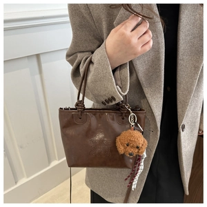 Detail of vintage brown tote bag with embossed lettering and plush teddy charm