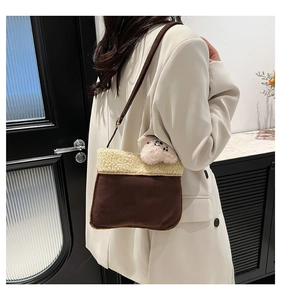 Detail of brown suede crossbody bag with white fleece trim and cute pink puppy pendant