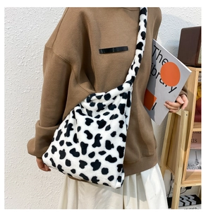Macro shot of large black and white cow print plush handbag with soft furry shoulder strap