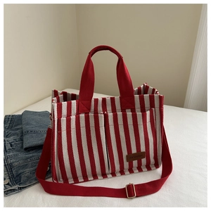 Detail view of red striped canvas tote bag with front pockets and fashion leather label