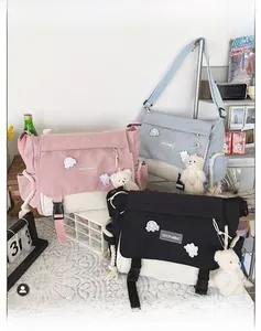 Detailed view of canvas messenger bags with cute patches and plush bear charms