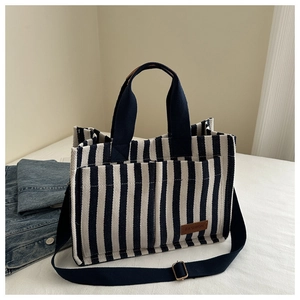 Detail of black and white striped canvas tote showing front pockets and leather label