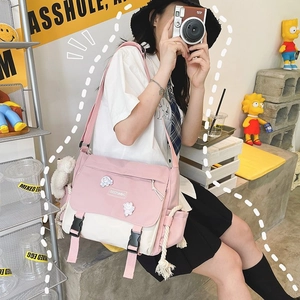 Detail of pink and white canvas messenger bag with cute badges and plush rabbit pendant