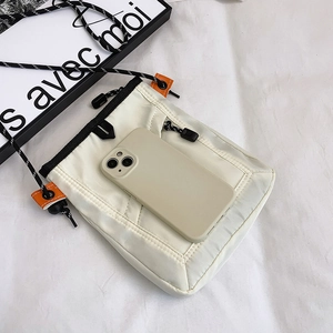 Close-up of cream utility phone bag with black zipper and dotted cord strap details