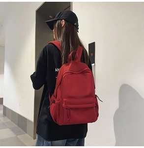 Rear view of a person wearing a large red water-resistant nylon backpack with black straps