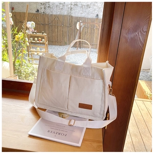 Detail of off-white corduroy tote bag showing textured fabric and front pockets