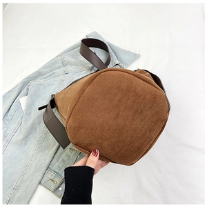 Detail view of the brown corduroy bucket bag showing the round base and soft ribbed texture
