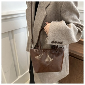 Detail of vintage dark brown tote bag with embossed letters and adjustable strap