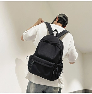 Close-up of black nylon backpack featuring durable front zipper pocket and paracord details
