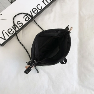 Internal view of a small black canvas crossbody bag showing the nylon lining and zipper