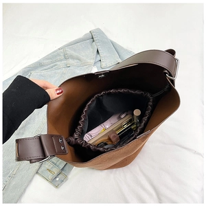 Detail of a large brown tote bag showing a drawstring inner pouch and spacious interior