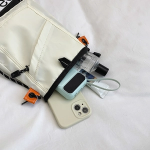 Detail view of cream nylon mini crossbody bag with phone compartment and black piping trim