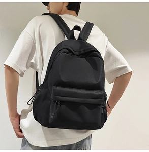 Detail of minimalist black nylon backpack featuring large main compartment and side drawstring pockets