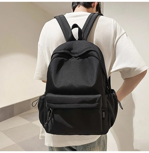 Rear view of a person wearing a minimalist black nylon backpack for daily commuting