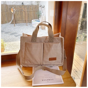 Close-up of khaki corduroy tote bag showing dual front pockets and leather fashion label