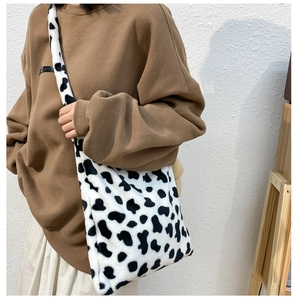 Detail of soft plush cow print crossbody bag worn by model with autumn styling