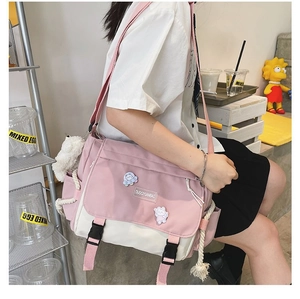 Detail of pink and beige messenger bag with cartoon embroidery and plastic buckle