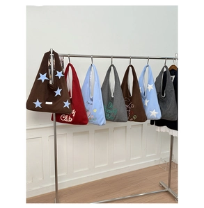 Multiple colorful knitted star tote bags with Dreaming Club embroidery hanging on a rack